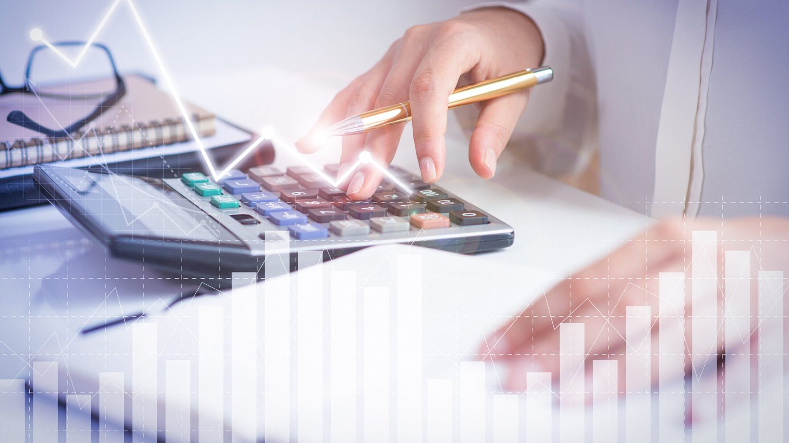 Accountant calculating profit with financial analysis graphs. Notebook, glasses and calculator lying on desk. Accountancy concept. Cropped view.